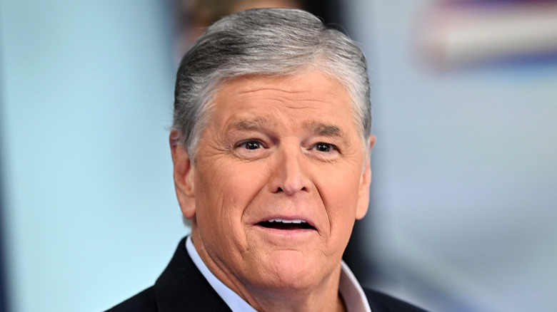 Sean Hannity hosting his show while wearing a blue collared shirt and dark blue blazer.