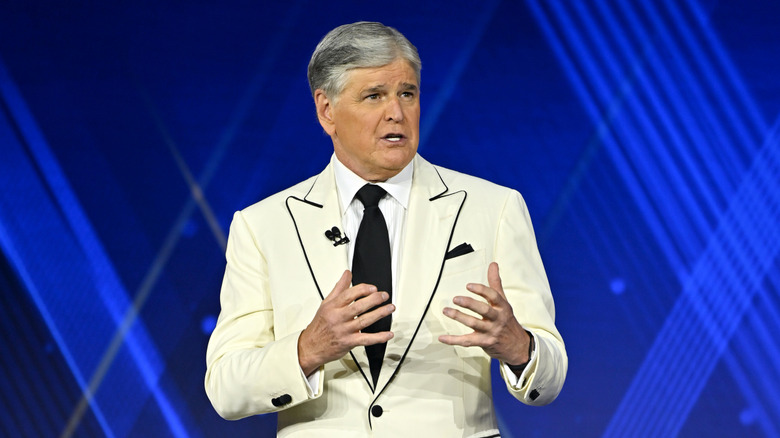 Sean Hannity in white outfit against blue background