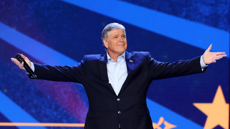 Sean Hannity standing on stage with arms outstretched