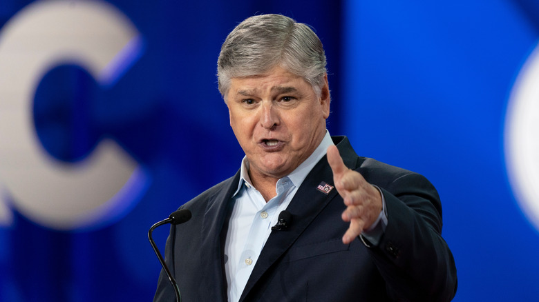 Sean Hannity speaking into a microphone and gesturing with one hand