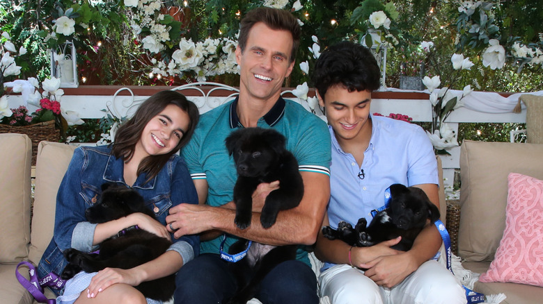 Leila Mathison, Cameron Mathison, and Lucas Mathison holding puppies and smiling.