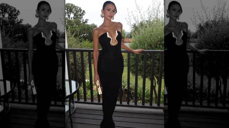 Nina Dobrev leaning on a balcony in her black dress.