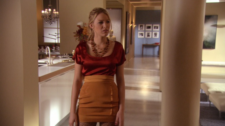 Blake Lively acting as Serena Van der Woodsen in a red and orange dress.