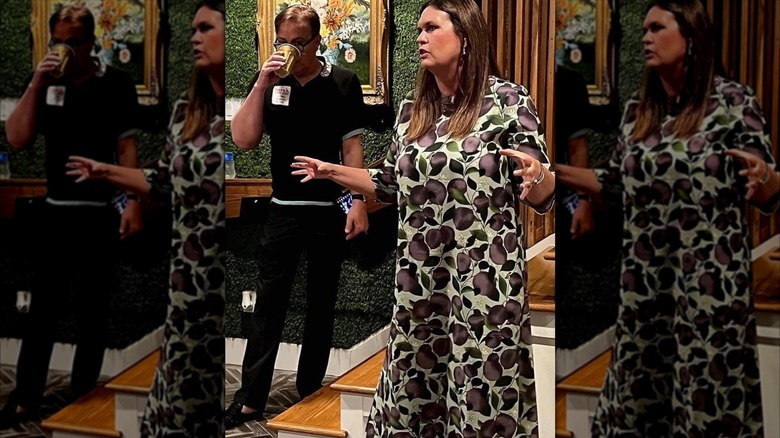Sarah Huckabee Sanders addressing the crowd in a plum colour printed dress