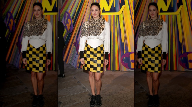 Shailene Woodley in a white top and yellow and black skirt