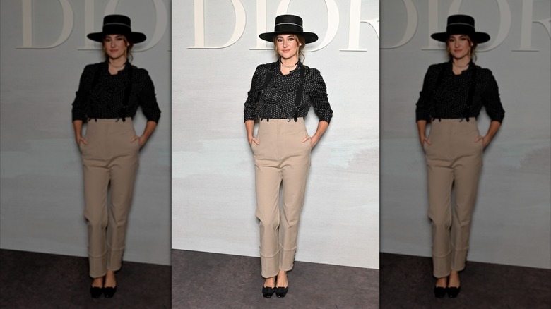 Shailene Woodley poses in a black shirt and khaki pants
