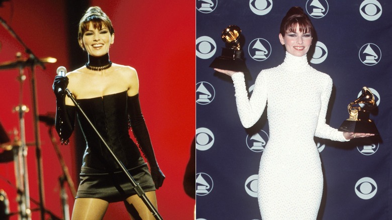 Shania Twain on stage in black outfit, holding up two awards in white dress
