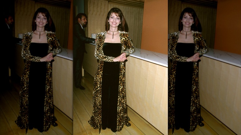 Shania Twain smiling in black dress and leather jacket
