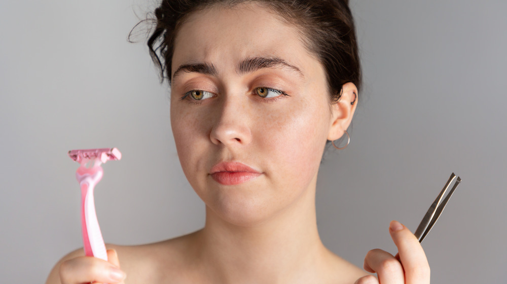 Woman with tweezers and razor