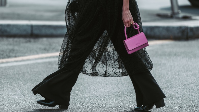 Woman walking in black sheer dress over pants