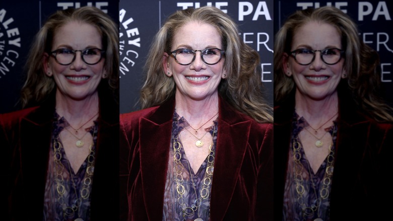 Melissa Gilbert with gray hair wearing glasses and a red jacket