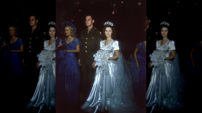 Colored photo of Shirley Temple and John Agar, accompanied by bridesmaids in the background