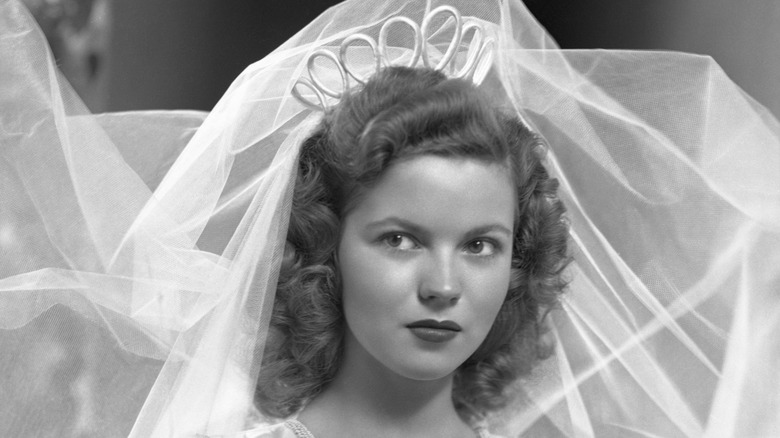 Shirley Temple with a large veil and looped tiara posing for a professional wedding portrait