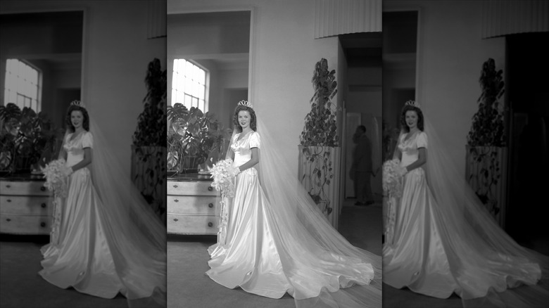 Shirley Temple poses for a professional wedding portrait in her dress, showcasing the long train and veil