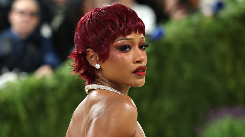 Keke Palmer poses with dark red hair and matching makeup