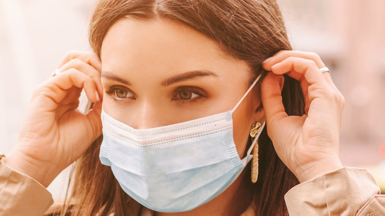 Woman fixing COVID-19 face mask 