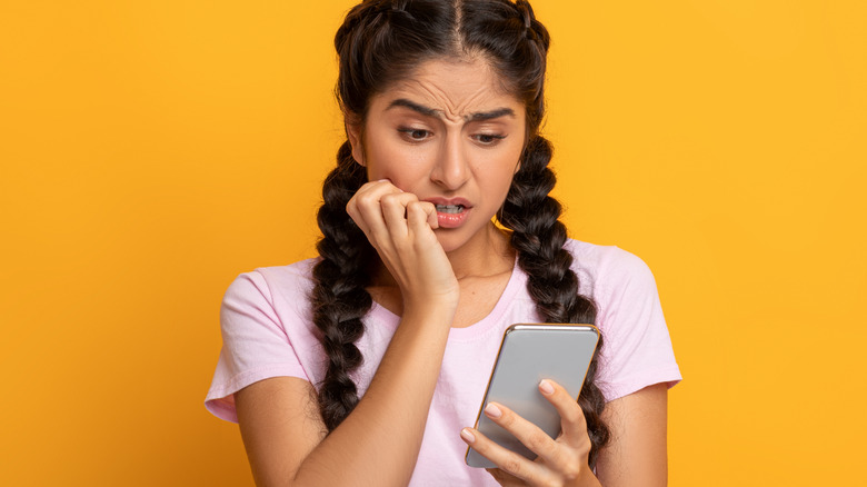 Woman staring at phone panicked