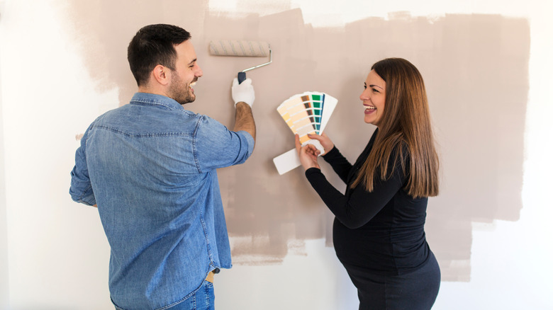 pregnant woman and spouse painting a wall