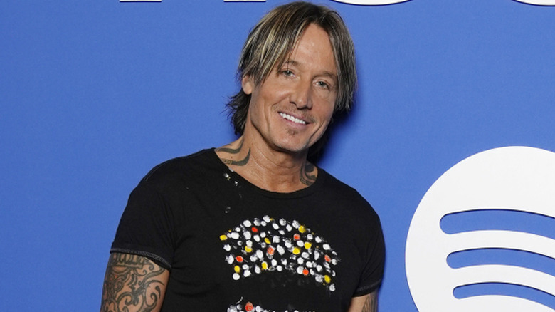 Keith Urban wearing a black shirt against a blue background