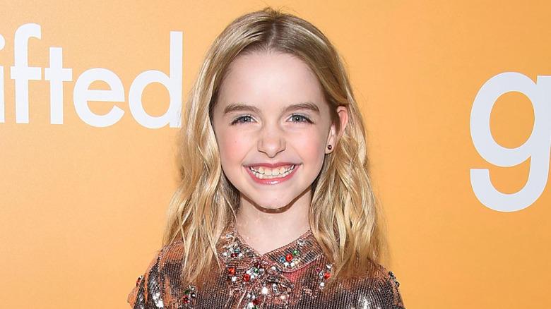 Young McKenna Grace smiling in front of an orange background