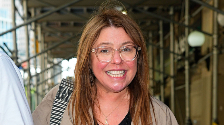 Rachael Ray smiling outdoors while wearing glasses with clear frames.
