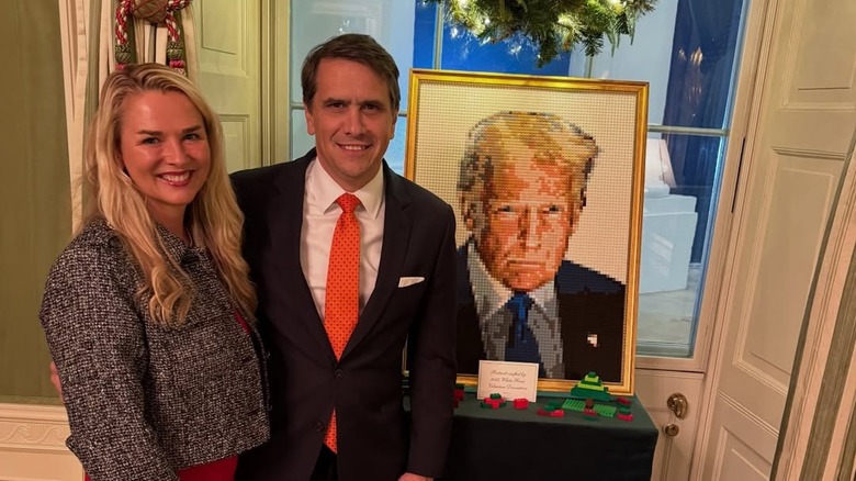 Kristine and Todd Blanche posing next to a Lego portrait of President Donald Trump