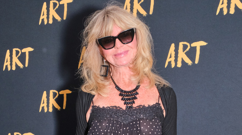 Goldie Hawn wearing black sunglasses and a black dress