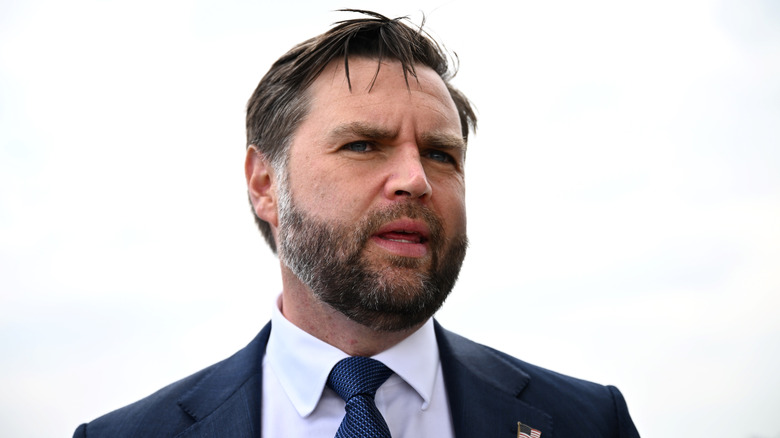 JD Vance grimacing in a suit against a white background