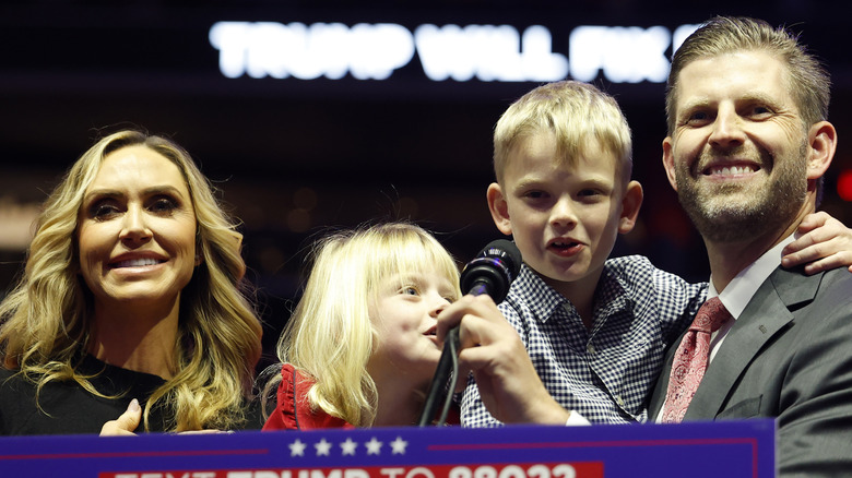 image of Lara Trump and Eric Trump amiling at a podium with their kids during a political event
