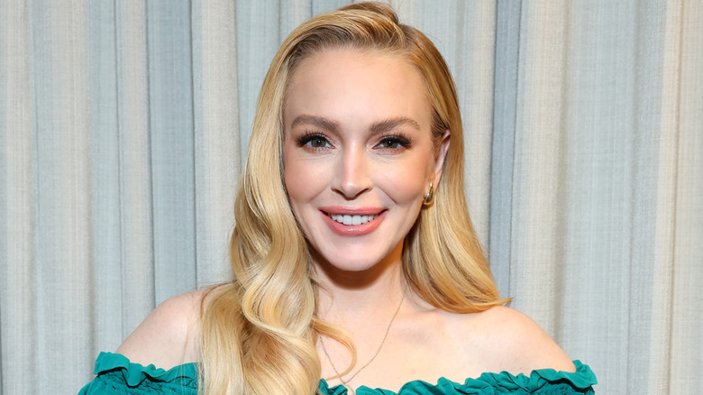 Lindsay Lohan smiling while wearing a shoulder-baring dress