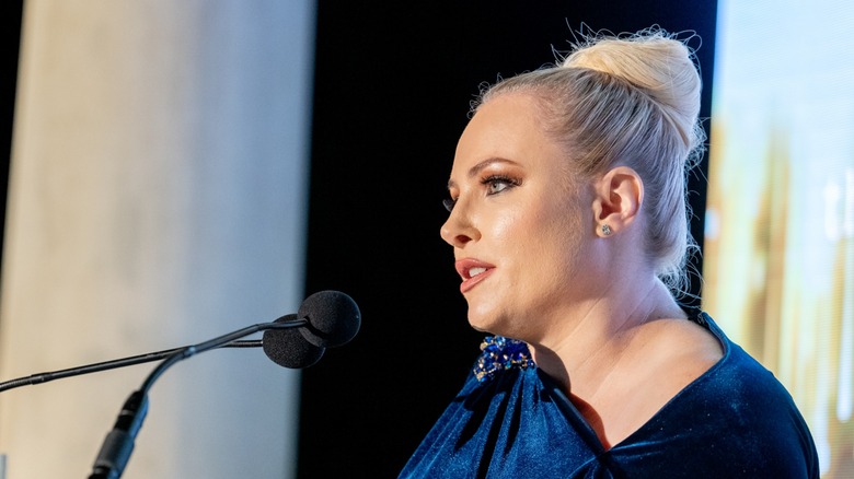 Meghan McCain speaking at a podium with her hair in a bun.