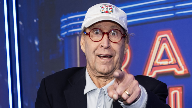 image of Chevy Chase with wide eyes and wearing a cap while pointing his index finger at the camera