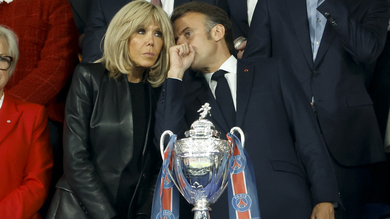 Emmanuel Macron whispering something to Brigitte Macron