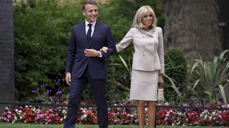 Brigitte Macron awkwardly holding on to Emmanuel Macron's arm