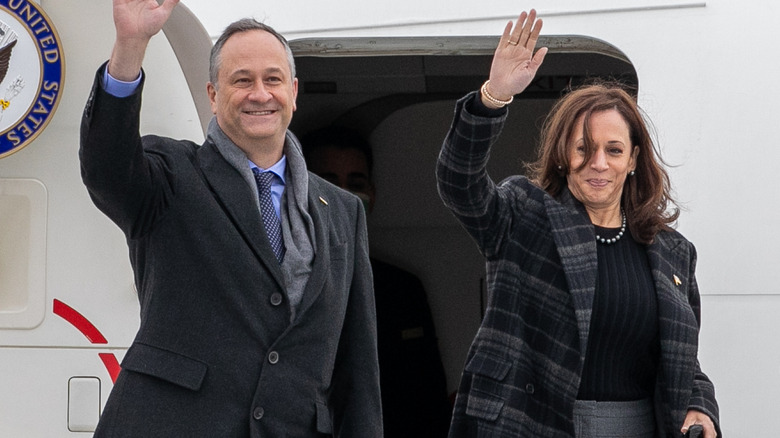 Kamala Harris and Doug Emhoff waving at spectators as they exit a plane