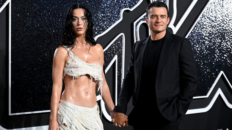 Katy Perry and Orlando Bloom posing for photos while holding hands