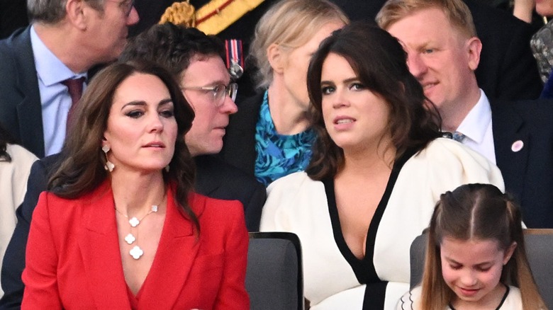 Kate Middleton and Princess Eugenie sitting among a crowd of people