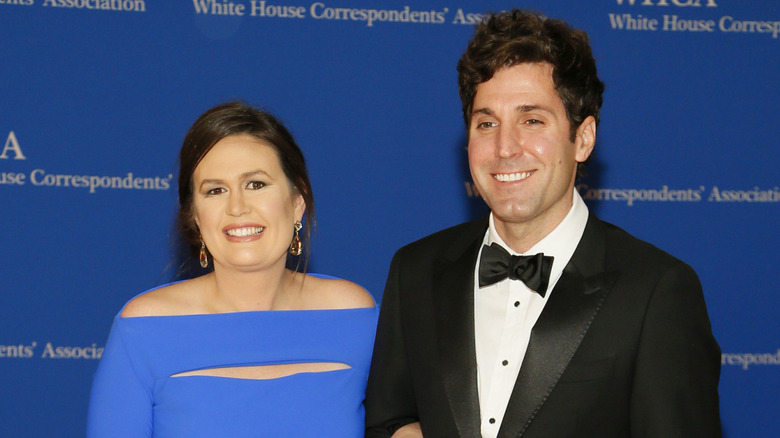 Sarah Huckabee Sanders smiling in a blue dress next to Bryan Sanders at the White House correspondents' dinner.