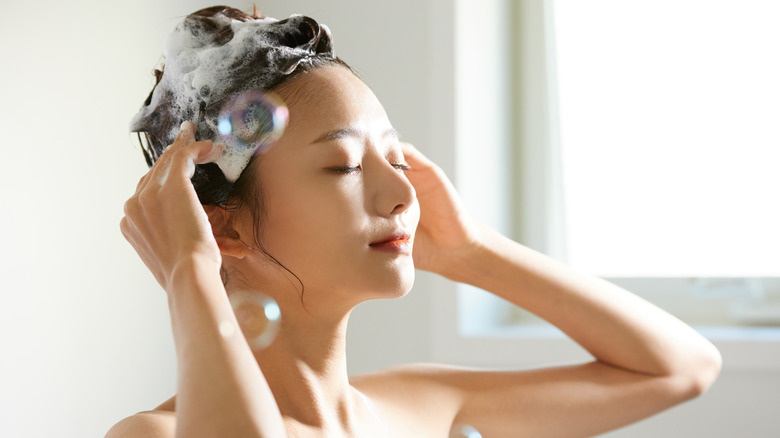 Woman washing hair with shampoo