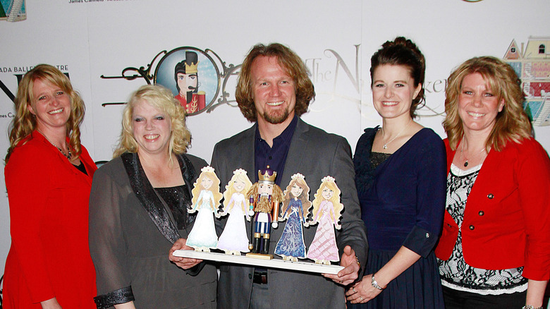 Kdoy Brown standing on a red carpet with his four wives