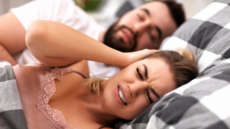 Woman trying to get sleep with a snoring husband