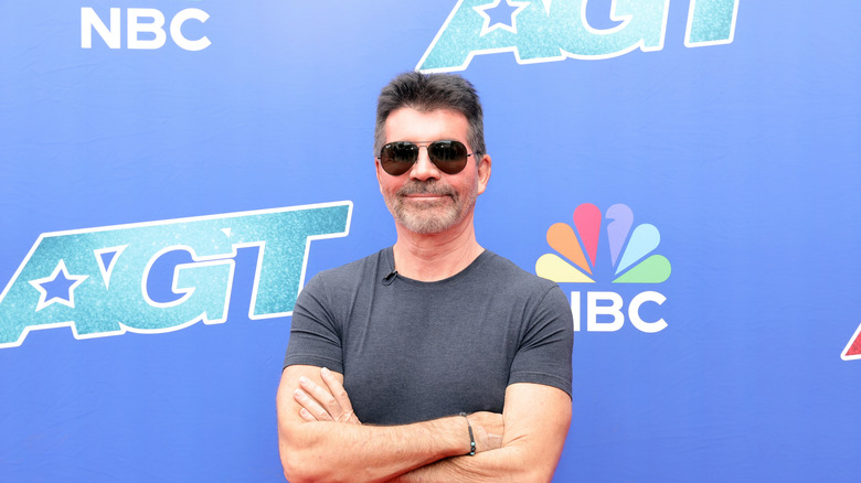Simon Cowell wears sunglasses and crosses his arms