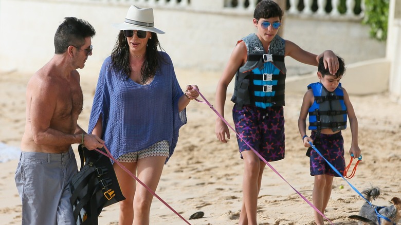 Simon Cowell walking with Lauren Silverman, their children, and dogs on the beach