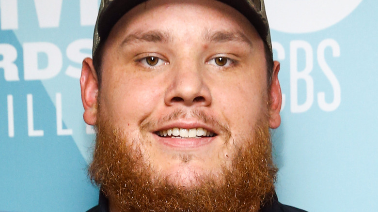 Luke Combs smiling with his awards