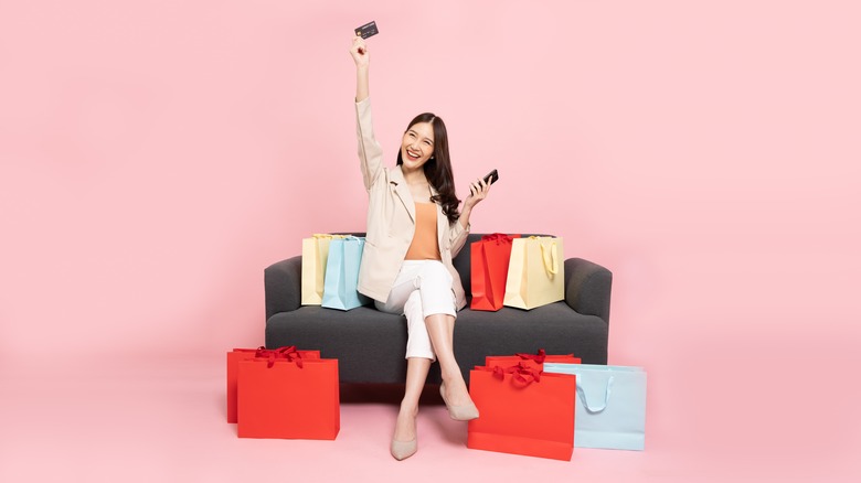 Woman on couch surrounded by shopping bags