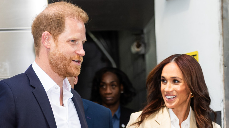 Meghan Markle and Prince Harry sharing a look and a smile while exiting a building