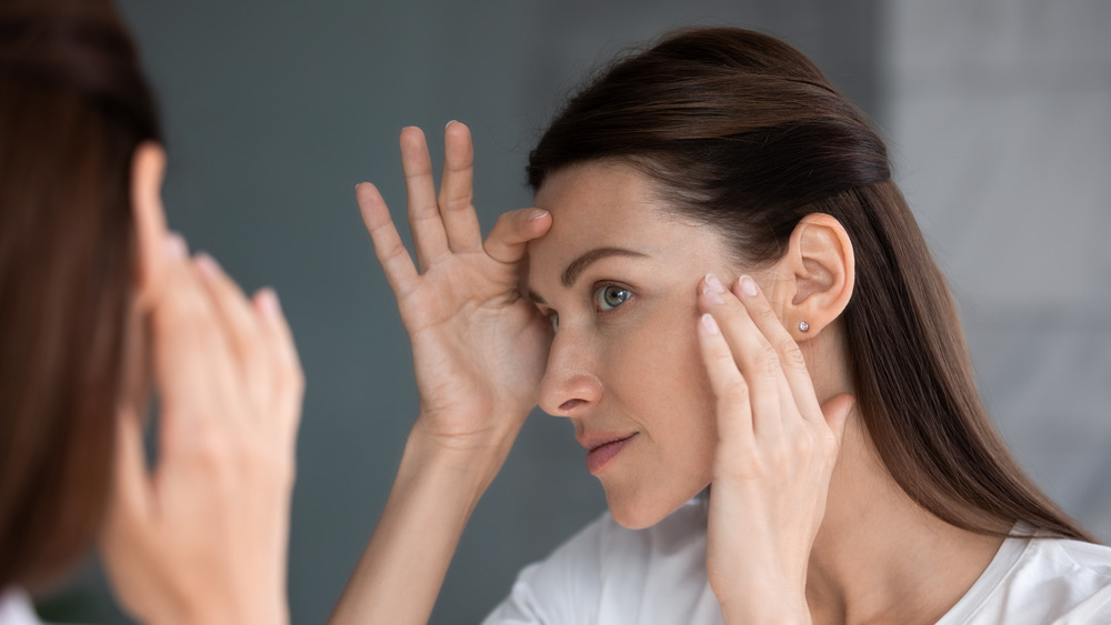 Woman looking at skin in mirror