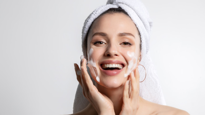 Woman in a head towel applies washing her face