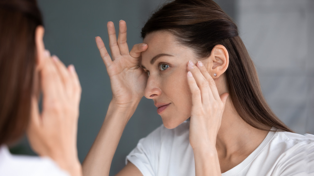 Woman looking in a mirror inspecting her skin