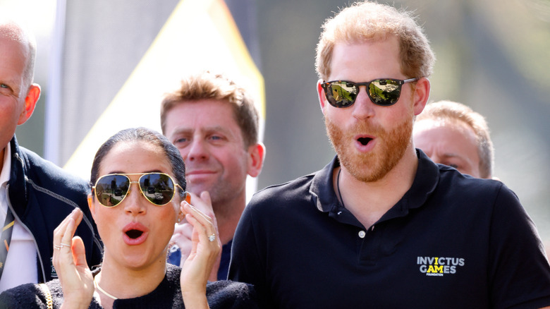 Prince Harry and Meghan Markle looking very shocked while watching an event